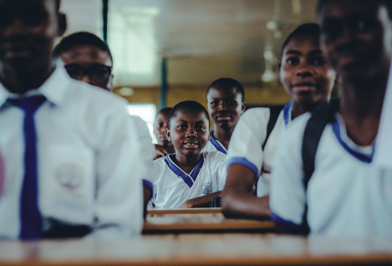 Smiling pupils in school uniform at their desks.
