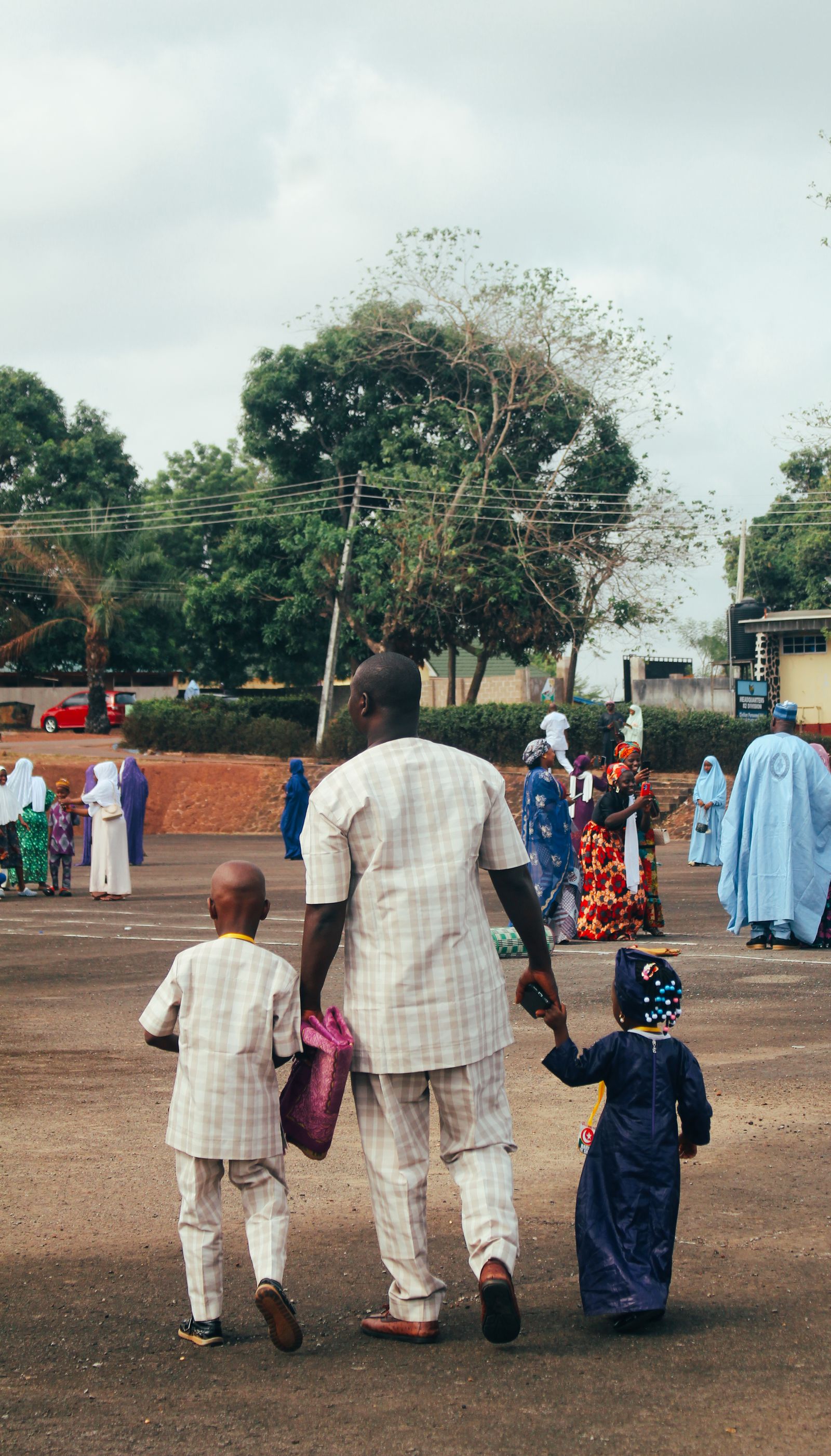 A father walking hand in hand with his son and daughter.